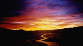 紫色天空下的弯曲沙漠道路