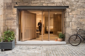 爱丁堡一个前铁匠工作室改造的一个36平方紧凑的公寓，其中有一个柔和材料调色板的滑动屏幕门，可以将卧室隐藏起来