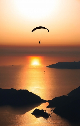 黄昏下的湖泊滑翔伞运动图