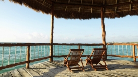 墨西哥海岸-休闲稻草茅屋下一对木质躺椅