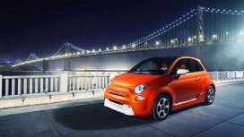 行驶在壮观夜景桥旁的橙黄fiat菲亚特500汽车