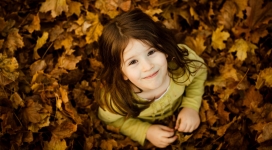 甜-站在落叶中抬头笑的小女孩
