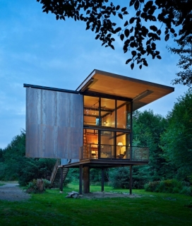 华盛顿国家公园周末度假舱-西雅图建筑师Tom Kundig作品-墙壁安装保护钢，地板高跷以防止水浸，整个房屋面积大约30平方米，外部采用四个钢柱为支撑，类似三角庇护所，里面有紧凑的厨房，双高客厅和用餐区和一个小洗手间