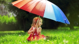坐在绿色草地上手握五彩伞的国外女宝宝壁纸