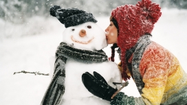 冬天里亲吻雪人的戴帽子美女