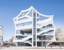 一个扇形大纲凹墙的建筑-位于韩国首尔，表面采用白色铝板，大包围玻璃窗格电梯和楼梯，周围的场地是一个巨大的圆形体育馆