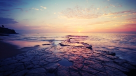 平静海滩岩的日落地平线