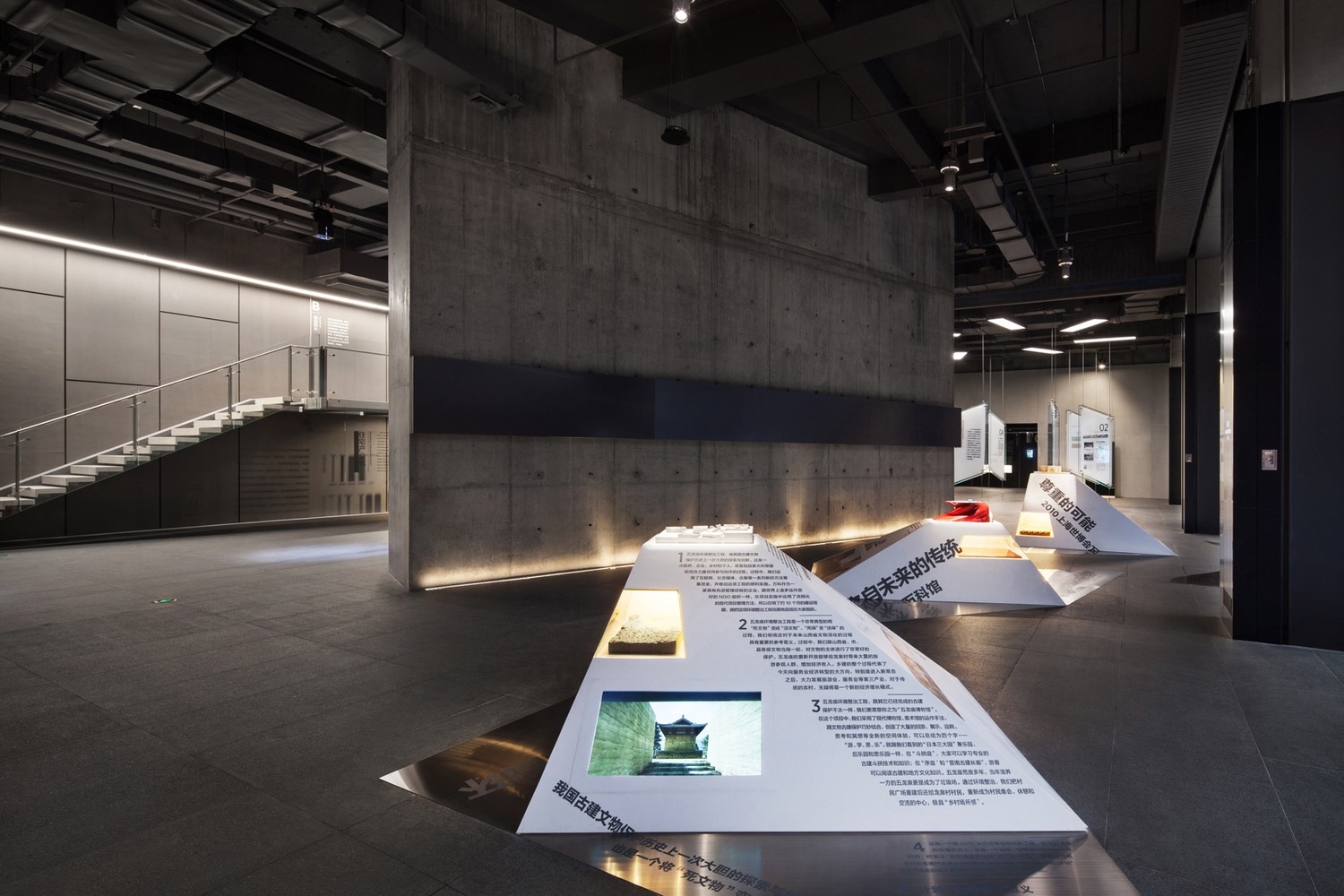 万科+是一个多主题的群展, 主要体现万科现在重要发展理念与成就。 为了突出每一个小主题的特点, 我们在展示设计上也根据内容再思考。 在关于万科工人施工与材料技术的展示上, 原展品是挂在墙上的, 我们利用三个悬浮的交叉展台把它们按标号顺序摆放, 既可以近距离看展品, 在空间上又形成一个动线关系。另外一个区域展示4个万科近年代表的建筑作品, 我们利用了山丘的设计, 既有模型台的功能, 同时四个侧面为文字和多媒体的展示,形成一个立体和可游乐其中的展区。另外我们还有两个比较独立的区域, 一个是小黑房展示万科的公益活动, 另一个是利用细线来围合的多媒体播放区。