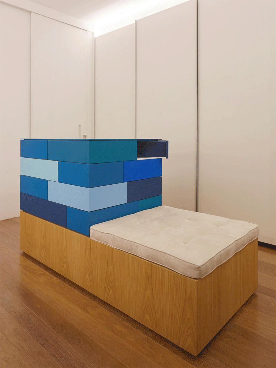 装饰中性的主卧室可通过更衣室进入,更衣室中间有一摞蓝色抽屉,一面墙壁上还内置木制梳妆台。