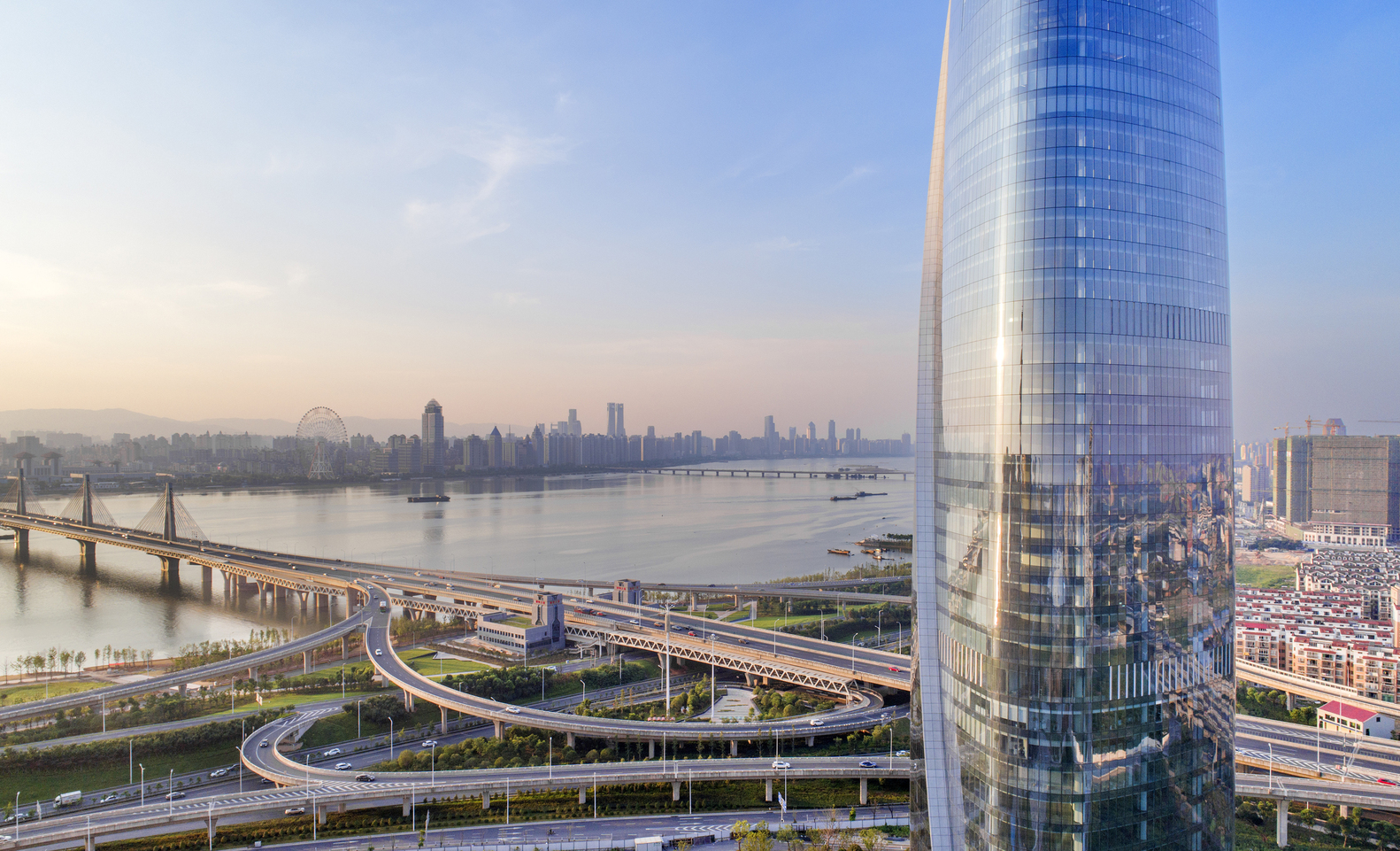 南昌新力中心总平面为带弧形的三角形,化解了三角形给人的尖锐的感觉,且合理避开与周边拟建建筑之间的视觉干扰。三角形切角核心筒压缩了核心筒面积,创造了更自由开敞的空间,连续的流线形平面形式使办公空间的景观视野最大化,创造了270°观江视域。