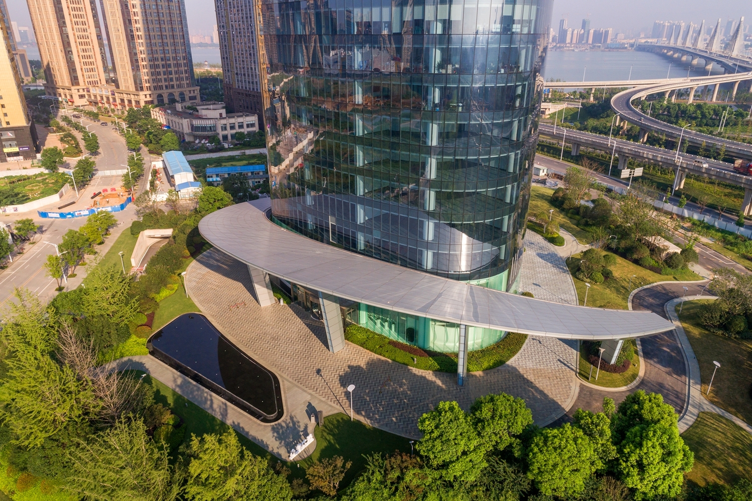 大雨蓬解决了出入口、落客等功能需求,也保证了消防环道的畅通,同时在节点设计上集成了排水与照明。其底层空间结合景观设计,对城市展现友好的开放姿态。