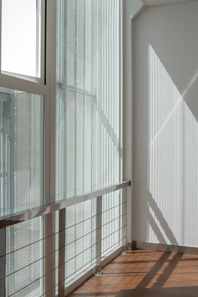 新的建筑外立面打破了原有建筑的竖向韵律形式,采用体块咬合和黑白红三色搭配的处理方式。一层以通透的大面玻璃为主,二层以黑白色压型穿孔铝板为主,结合红色耐候钢板及深灰色铝板雨棚。整个建筑褪去了厚重的墙面外衣,变的通透轻盈,艺术感极强。高低错落的窗洞,和半透明的穿孔板表皮,使得建筑室内拥有丰富多变的光影效果。夜幕降临的时候,室内的灯光透过半透明的表皮,释放出朦胧柔和的光线,更具艺术气质