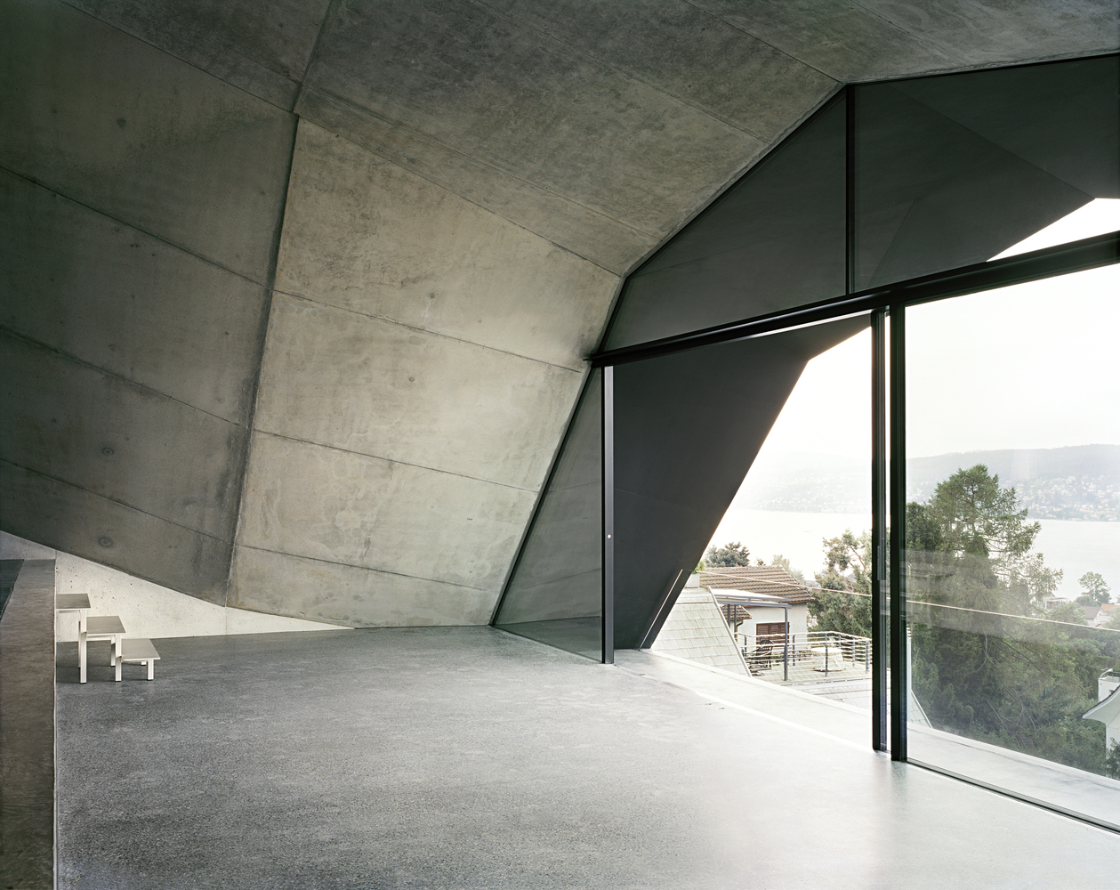 根据分区条例的规定,这个项目将土地的利用发挥到最大。扭曲、倾斜的屋顶直观地反映出对应的法定分区制度。屋顶的每一点都是规定的屋顶高度的最大限度,侧面的凸起增高了它不规则的形状。屋顶、地板、墙面和楼梯都使用了相同的黑色材料,使屋顶和墙面成为了和谐的一体。整体的色调强调了建筑的雕塑感和立体感。