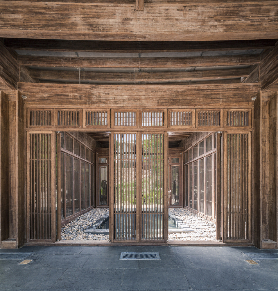 西侧连接接待大堂的部分,是一个几乎完全契入山体的部分,主要布置了厨房、餐厅包间、小展厅等辅助功能。一个巨大的单坡屋顶顺山势倾斜,与接待大堂的屋顶形成叠落的关系。为了达到更轻薄的形体效果,建筑主体采用竹钢搭建,竖向的立柱每根都为承重住,从而达到均匀受力的效果。“柱”与“梁”的连接部分采用简单的交错堆叠起来进行构造的方法,使其在形式上产生出类似斗拱结构的效果。而屋顶则采用GRC预制板,直接“平落”在竹钢框架上;屋顶面层采用金属瓦,而非传统瓦,这些做法都极大的减轻了屋顶重量,使整体结构轻量化,更传达出一种具有现代气质的南方建筑的秀美。