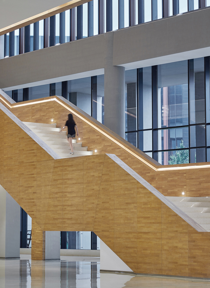 “大峡谷”中庭中,一道上有镂空方洞的木饰面墙所构成的景观构筑体格外醒目,它沿地面蜿蜒、起伏、翻转、缠绕,最终围合出一个轻盈、自由而又不失私密的休闲洽谈空间。