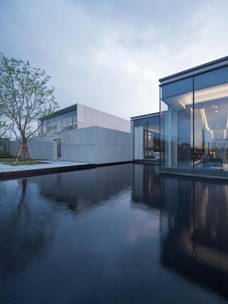 建筑位于杭州萧山科技城, 场所内临湖的景观优势使其增添了份江南水乡的灵动。“人“字型斜坡屋顶与极简白墙、黛瓦元素给人以鲜明的视觉印象,形成连续而富有韵律的整体界面。入口处采用仿木杆元素,形成半透的帘幕效果。建筑立面与景观小景的结合,刻画了一副江南山水的绝妙画卷。