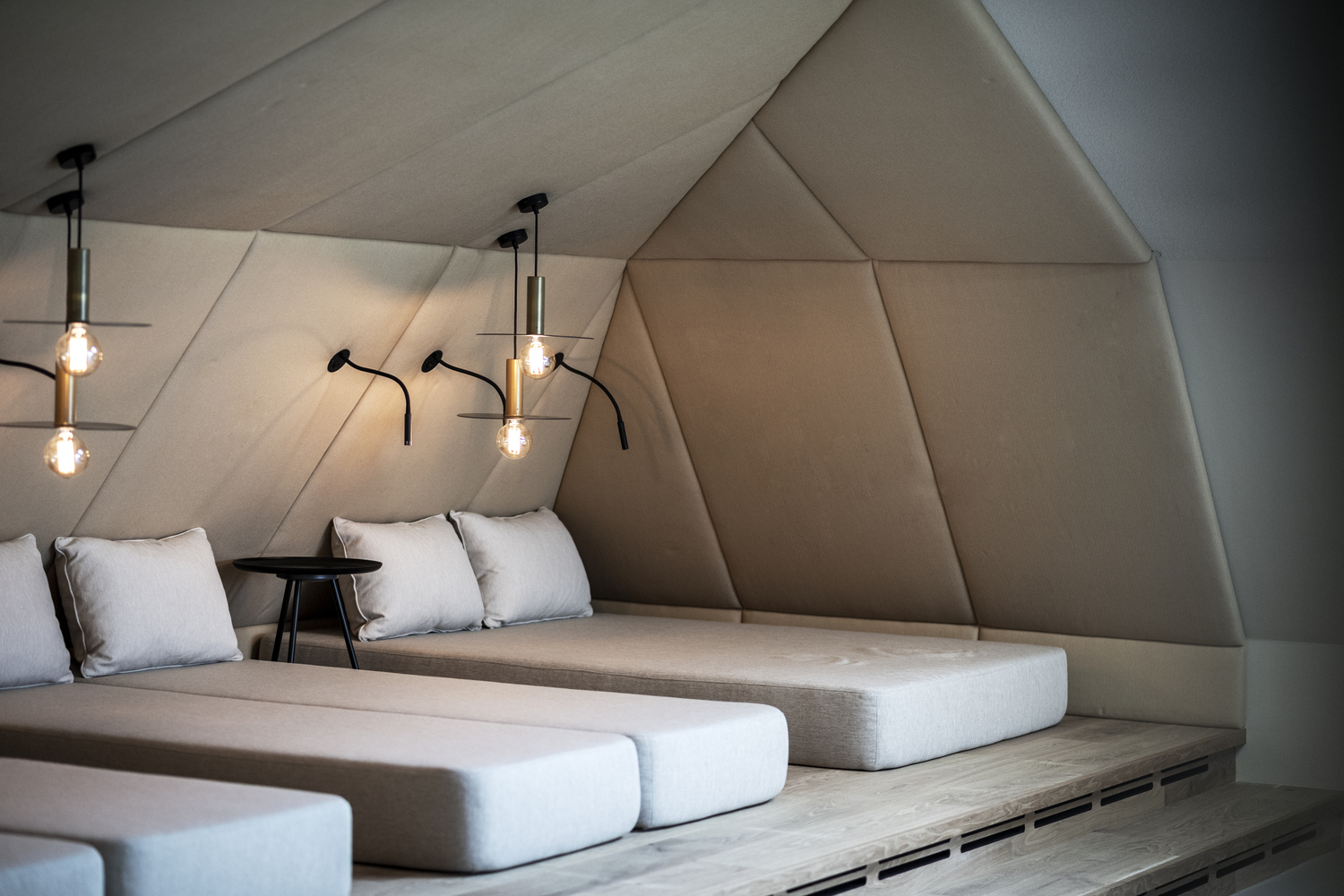 公共区域选用无缝树脂地板作为要素使房间呈现连续性流动。木地板在地面堆叠成“岛”,区分出休息室与餐厅的不同空间边界。这个概念也被沿用到顶楼水疗区。不仅在水疗和公共区域,特别是客房和套房的内部空间每个角落都受到设计师的热切关注。套房中飘窗是重中之重,它为休闲区提供了壁炉、独立浴缸或沙发景。空间由层层嵌套的壳体隔开,墙体、地板和天花板使用同样材料装饰。木材让空间显得更为均质、华贵且温暖,极具吸引力。