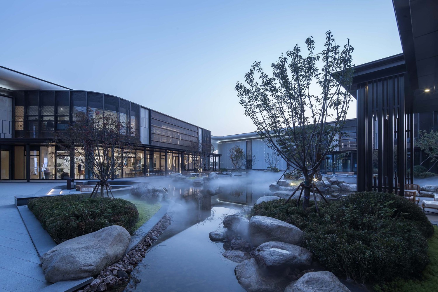 高达10m的现浇混凝土伞形柱无疑是整个建筑的主角。位于两个转角的伞形柱向上延伸成整片的“C”型平屋顶,将整个建筑的体量统筹于屋顶之下,形成统一、简洁的建筑形象。东侧平屋顶覆盖新中式立面风格的社区配套中心,使现代与新中式有机结合,形成城市界面与社区环境的良好过度。