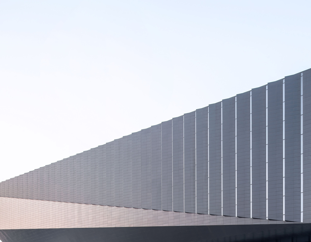 一层公共服务区,有展厅、QQ商店、咖啡厅。将印刷玻璃作为基底,像湖面晨雾那样有白色漂浮的姿态,和场地环境的对话也很好。二层以上为办公区。沿着湖面用隔层大露台和大台阶连接湖岸,可以是午间休憩和夜晚派对的地方,也可以从办公室直接走到湖边树林里工作。