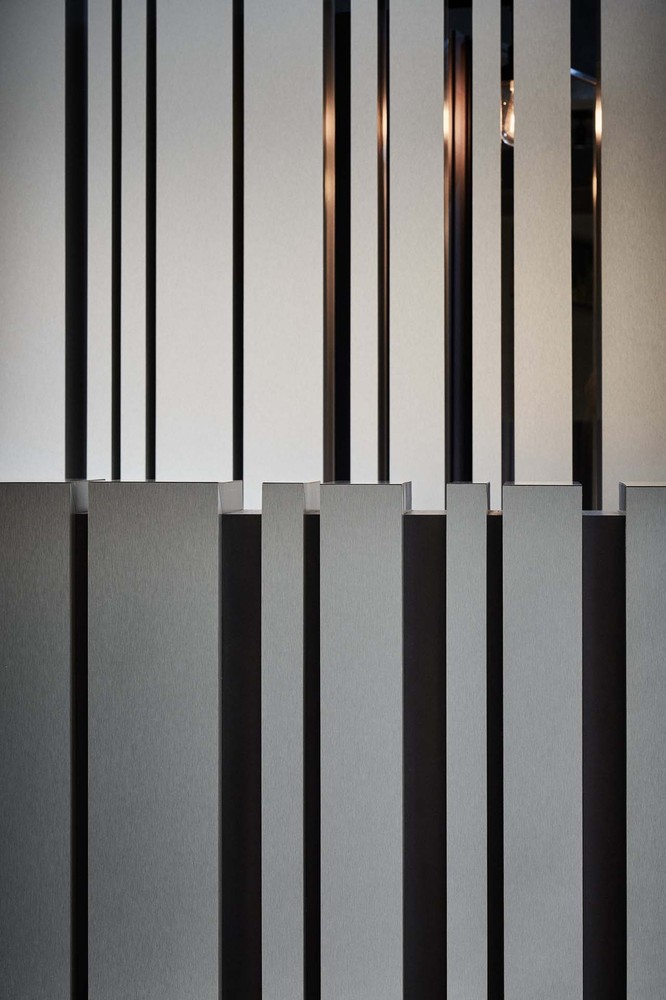 工作区在镜子后方各自隐藏了独立的滑动式收纳衣柜,让顾客在剪发时能拥有自主性较高的收纳隐私,同时也将线性的剪裁方式,由镜柜延续至染剂调色吧台以及冲洗区隔屏,让工作空间保持一致性的沉稳色调,跟全白色调的接待空间有所区隔,把空间里较需要隐密性的剪发视觉重新还给享受发艺沙龙的顾客