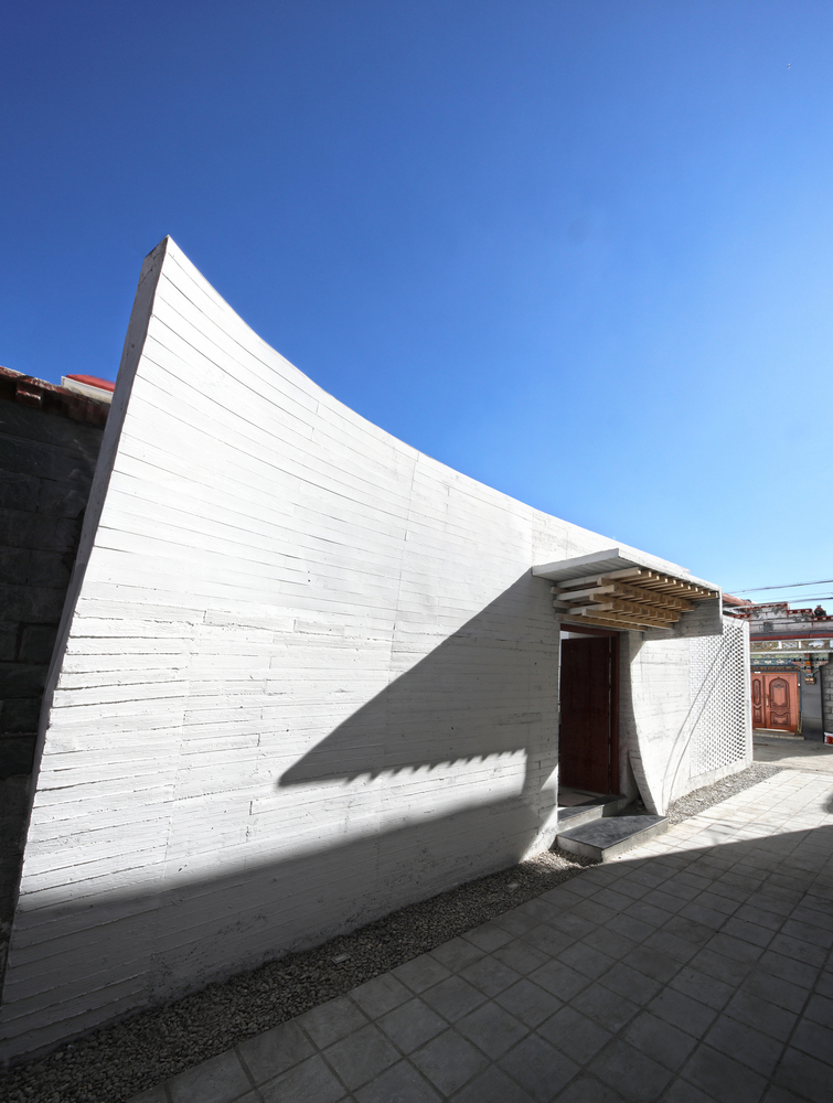 拉萨被誉为日光之城,阳光是对一家人居住行为当中非常重要的元素。但是光并不意味着无限制的光,而是一种被控制的光,被设计过的光。传统的藏族起居空间里,对光的控制体现在“冬室”和“夏室”的区别。开窗规律为下层窗小,利于保暖,故为“冬室”,上层窗大,利于通风,故为“夏室”。一层外墙很少有开大型窗户,这样形成的传统藏式的院落往往是一种内向型的空间,并通过高高厚厚的院墙营造私密、肃穆、威严的气质。 但是在新式的厨房以及厕所等功能空间的要求,很多不得不在外墙开一些小型的功能性洞口。因此在新的设计中,在保持外墙私密的前提下,通过撕裂几处裂缝,来为室内的空间提供采光与通风,满足功能性的同时,将外墙的界面处理的更加柔化与模糊。另外,建筑师观察到当地人在翻新当代民居的时候,特别注意外墙材料的运用,一般他们会使用如拉萨石等天然建筑材料。建筑师在改建部分的建筑上,使用混凝土整体浇灌的技术,一次成型的混凝土外墙运用混凝土木纹肌理产生的白色墙面, 通过实木质感与人尺度拉近,打破常规高高的外墙与人的隔离。