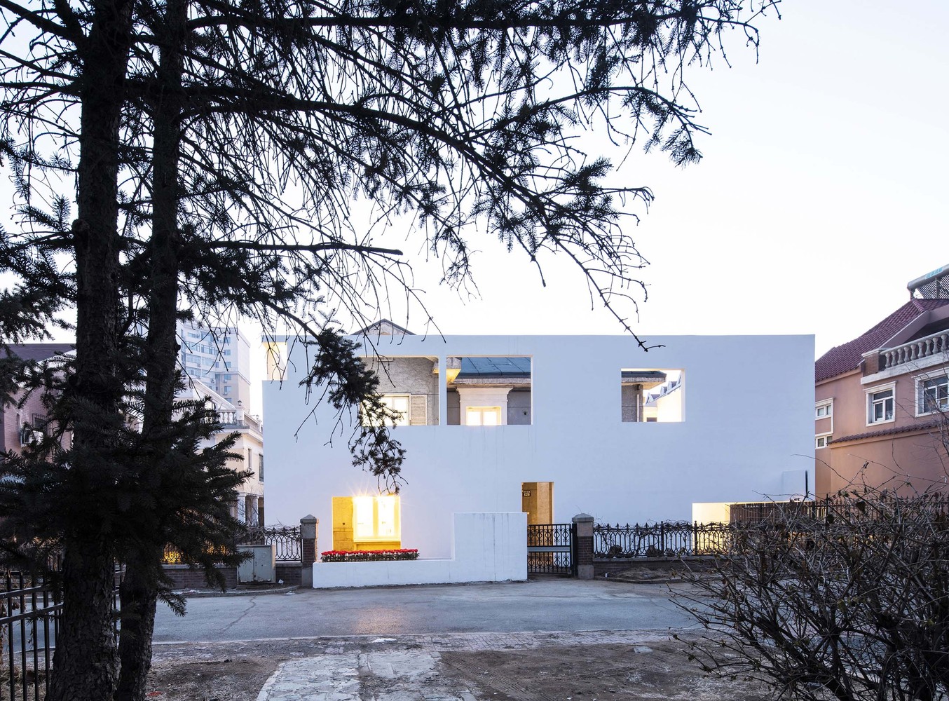 设计概念来源于外墙的爬藤,以及园区外围象征城市的高楼大厦之“墙”。完整保留原建筑外立面厚重的质感,建造一个轻盈白色的外部建筑,重新整理并定义与突变的城市关系。新建筑与原建筑之间形成了两种质感的街道空间。白色的围城与邻里建筑隔离开,并通过墙洞与城外的城市及邻里对话,形成另一个城市里的城市,花园里的花园。