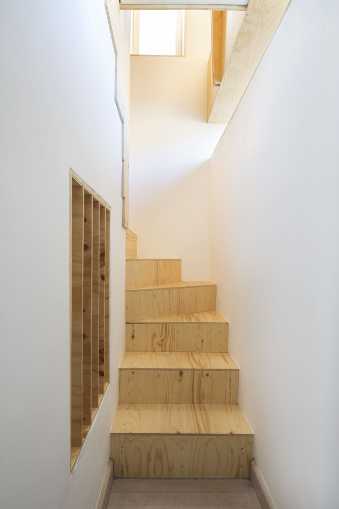 阁楼图书馆通过对阁楼空间的创新性调整和重组,创造了10平方米的新建筑空间。与工程师Corbett&Tasker合作,开发出了一种富有表现力的结构解决方案,用结构胶合板拱的框架代替斜木构件。屋顶结构在整个工程中保持不变,从而节省了施工现场防雨的额外费用。在投标前,要求对胶合板拱门、楼梯、货架、长凳和桌子的供应、切割和交付进行报价,以便投标承包商不会高估明显复杂的建筑方案的风险。