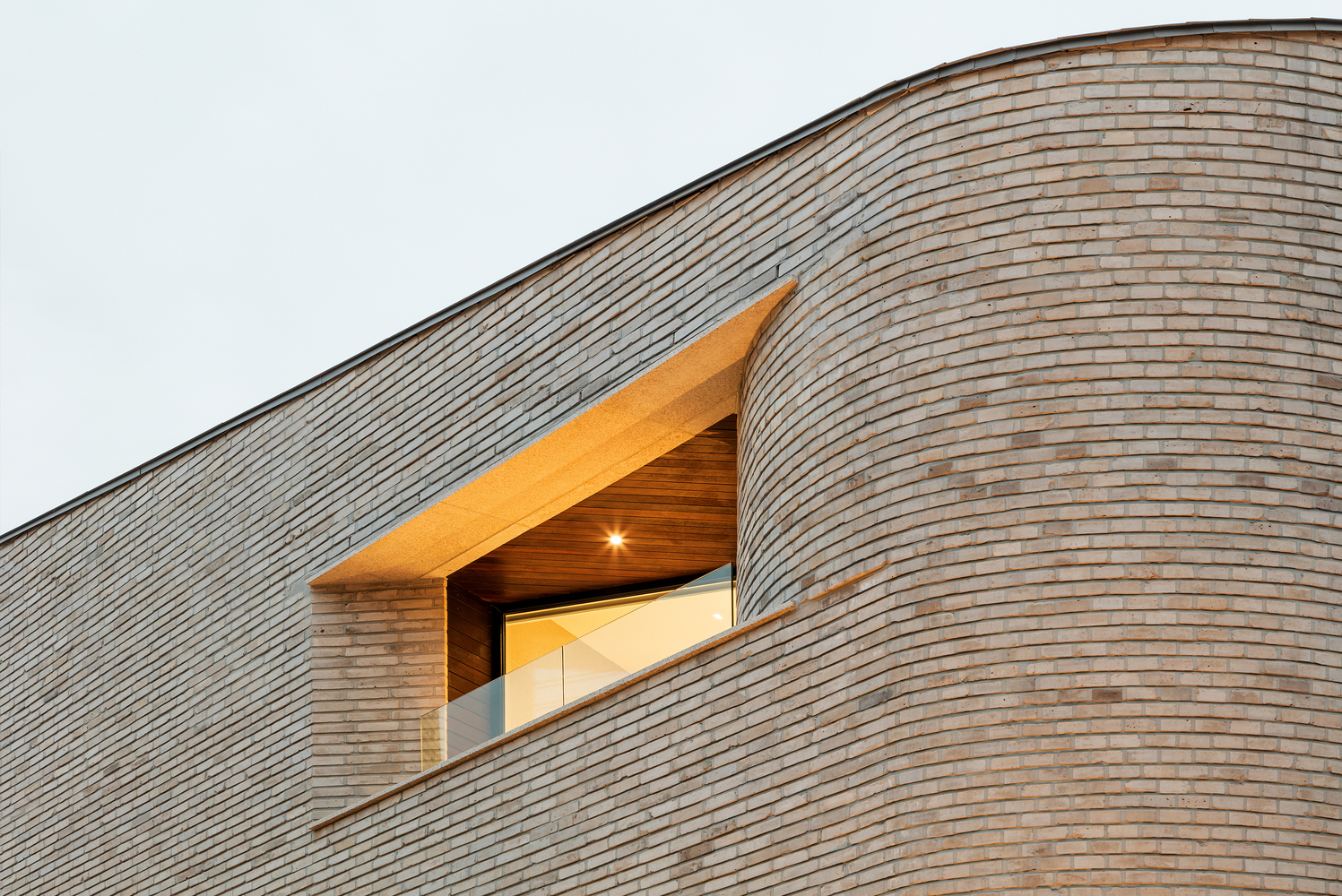 倾向弧形边缘的三角墙屋顶为这座宁静的住宅增添了迷人的韵律。每个房间的露台作为联系外部的媒介的同时,也把内外互动控制在一定范围内而不至于屋主的隐私被侵扰。形状各异的窗户让建筑脱离束缚,而有了一丝开放感。与此同时,从钝形到弧形的窗户边框所带来的节奏感无疑抓住了外人的眼球。