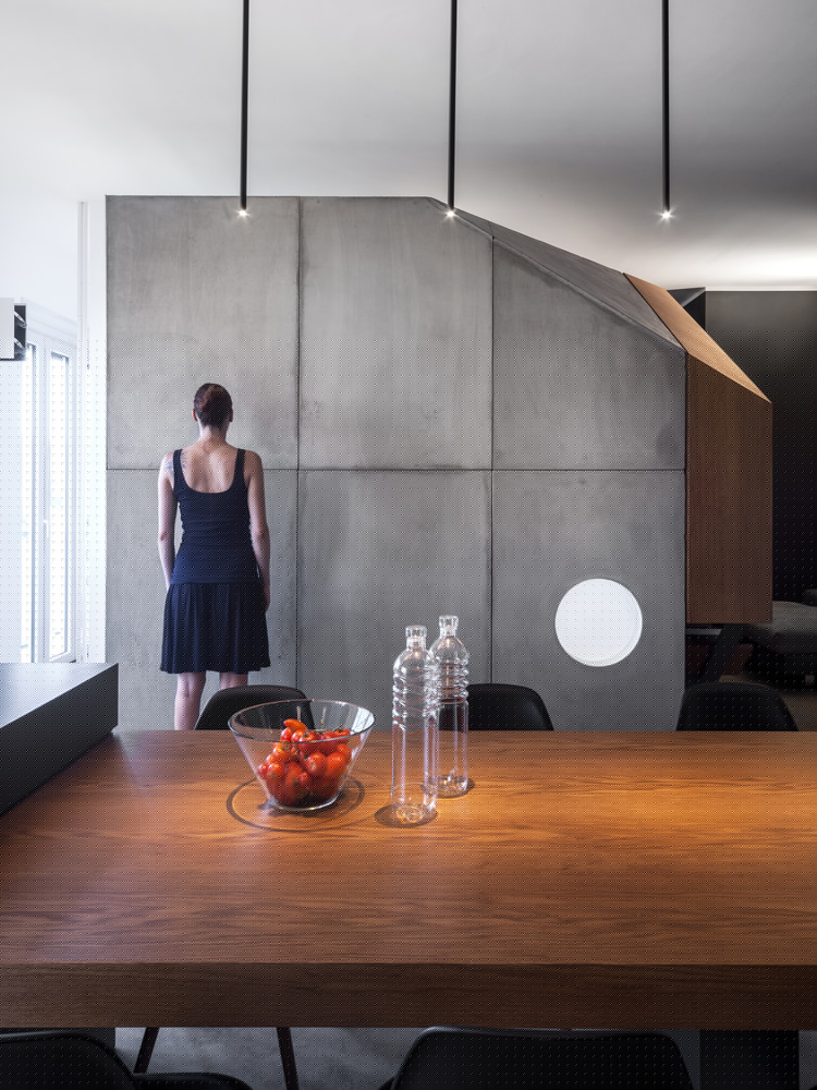 厨房为深色,餐桌采用橡木制成,穿透到工作区,包围着结构的柱子。 浴室呈细长形,由混凝土搁板组成,搁板支撑着洗脸盆。淋浴区采用白色环氧树材料,为整个深色的浴室引入自然光线。