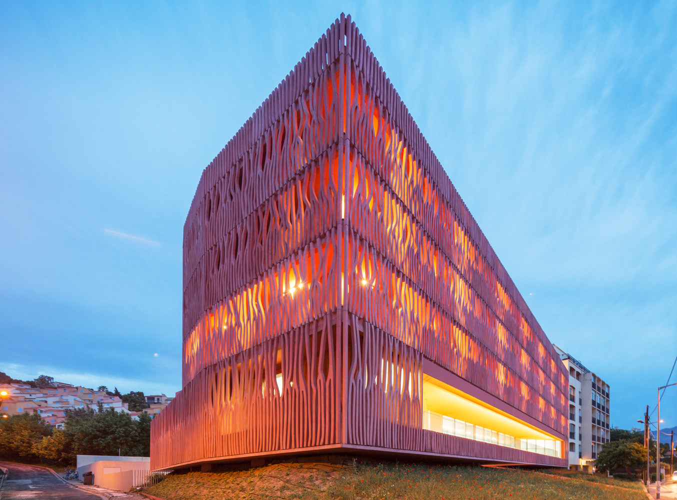 建筑位于海边,沿着现有的天空、地面还是地平线的地形继续延伸。 它重新创造了视线与景观之间的关系,适应城市的建筑高度规划。赭色的色调回应了周围山丘和由内陆耕作梯田组成的土地。这些被葡萄园覆盖的山丘高耸于大海之上,闪耀着氧化铁深沉的泥土色调。