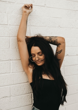 靠墙伸懒腰的纹身眼镜女孩