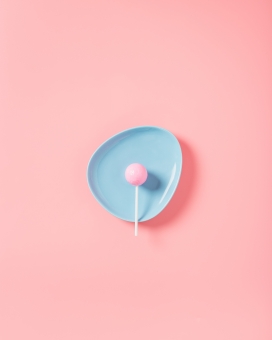 粉红色背景蓝碗中的棒棒糖