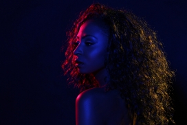 彩光照射下的卷发黑人女子