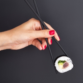 用筷子夹紫菜香肠寿司的女子手
