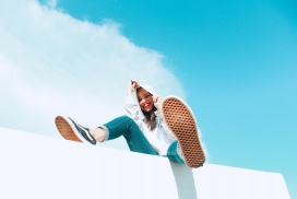 仰拍坐在白色墙壁上的女孩