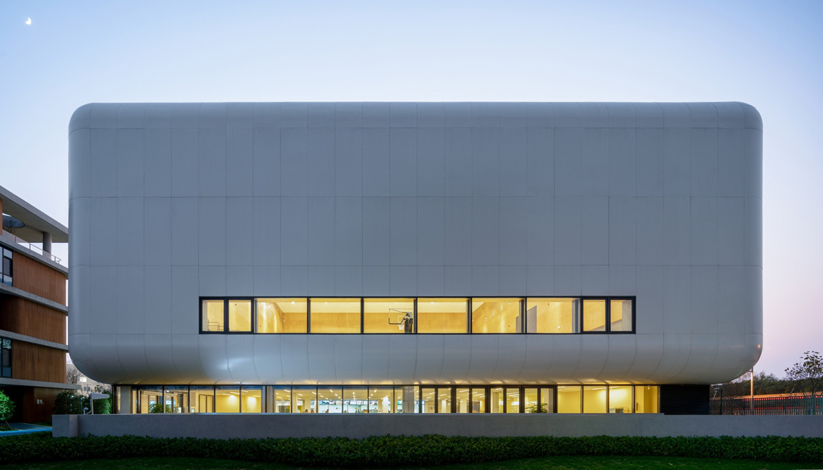 东侧较大的“气囊”是一个多功能的风雨操场,这里可以作为篮球、排球、羽毛球、跆拳道、击剑等运动的场地,旁边还分布有一些小型健身房。其内部空间明亮干净,大跨度的空间没有一根柱子,放眼望去只有温暖的竹板饰面、深灰色的防撞墙和两侧可伸缩的阶梯座位。太阳光经过长条形天窗的过滤进入室内,白天完全不需要人工照明,让学生们沐浴在充足的漫射光下,进行丰富多彩的室内活动。