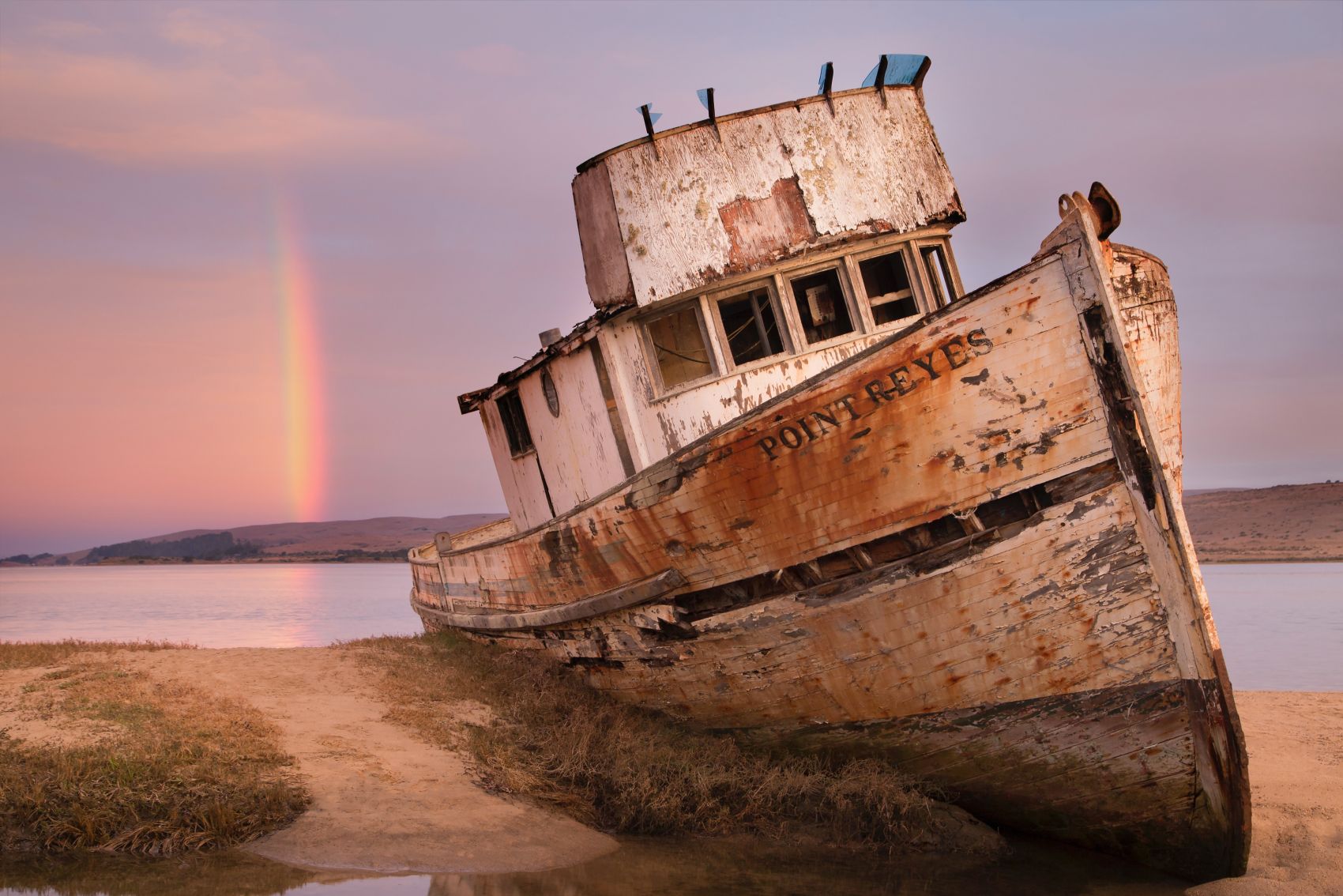河床边遗弃废船上的彩虹图片