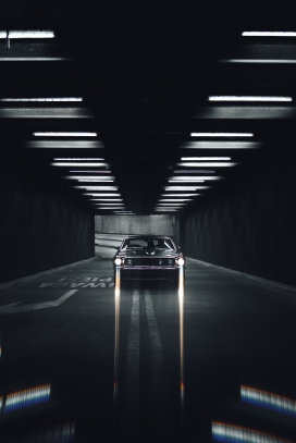 黑色隧道开着灯光的老爷车