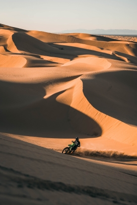 金色蜿蜒沙丘上的摩托车骑行者