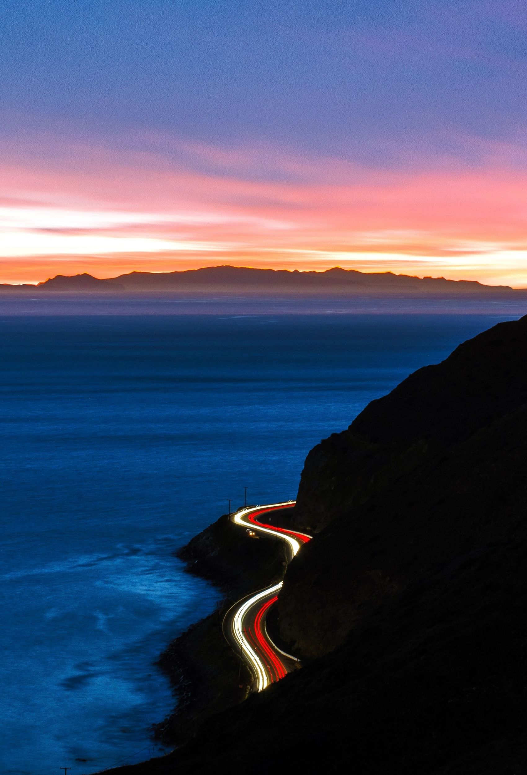 彩霞下的海岸线车流光轨图图片