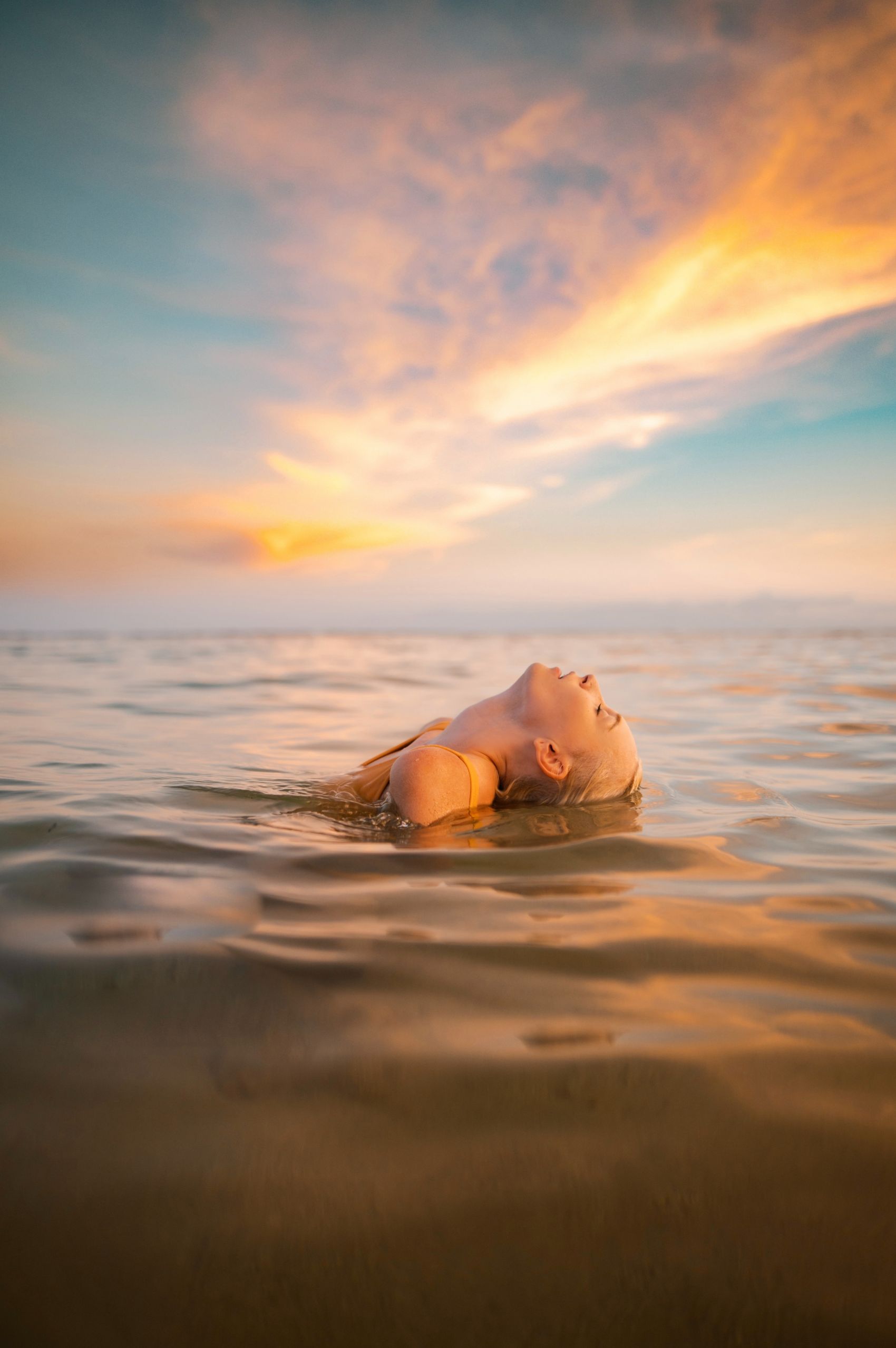 晚霞下水中仰泳的女子图片