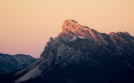 暮色金辉山峦：橙粉天幕下的岩峰光影自然图景